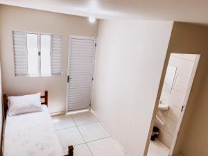 um pequeno quarto com uma cama e uma janela em Pousada alojacampinas em Viracopos
