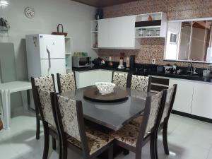 cocina con mesa, sillas y nevera en Linda Casa 4 Quartos Castelhanos ES, en Anchieta