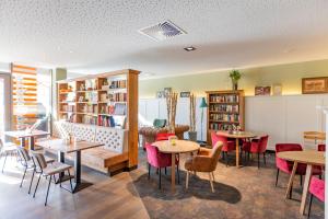 ein Restaurant mit Tischen, Stühlen und Bücherregalen in der Unterkunft Hotel MODI in Dachau