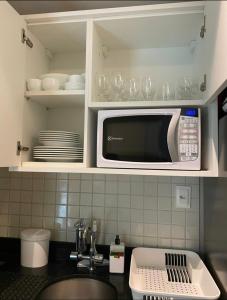 una cocina con microondas y algunos platos y vasos. en Flat Eco Summer Tambaú Apto 2Qts, Cozinha completa, en João Pessoa