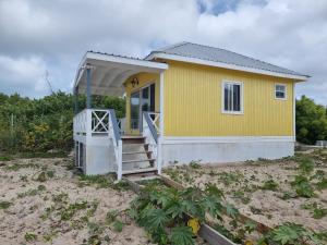 une maison jaune avec une terrasse couverte sur la plage dans l'établissement Comfortable 1-Bed Cottage in Codrington Barbuda, à Codrington Village
