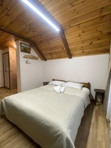 ein großes weißes Bett in einem Zimmer mit Holzdecke in der Unterkunft Затишок в Карпатах 1 in Slawske