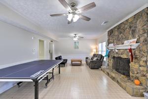 a living room with a ping pong table and a stone fireplace at Immaculate Suwanee House with Pool and Game Room! in Suwanee