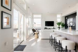 a kitchen and living room with a bar and stools at Chic Gallery Loft - Amazing Deck - Zuni Lofts in Denver