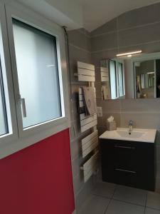 uma casa de banho com uma porta vermelha e um lavatório em Campagne à la Ville em Pontivy