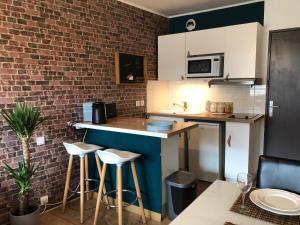 a kitchen with a counter and a brick wall at Studio avec balcon & parking gratuit - Tours Gare in Tours +13 photos