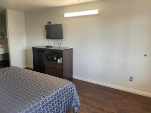 a bedroom with a bed and a flat screen tv at Garden Inn Motel in San Antonio