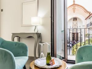 une chambre avec des chaises et une table avec une bouteille de vin dans l'établissement Amphora Alojamiento Ecija, à Écija