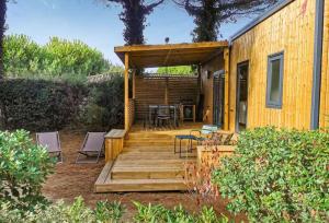 a house with a wooden deck with chairs and a table at Camping Le Suroit in Le Bois-Plage-en-Ré