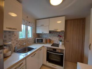 a kitchen with white cabinets and a sink and a microwave at Mandola suite in Argostoli