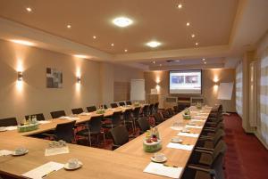 uma sala de conferências com mesas e cadeiras longas e um ecrã em Hotel Falkenhagen em Pritzwalk