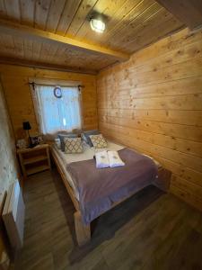 a bedroom with a bed in a wooden cabin at Myczkowianka Sadyba in Uherce Mineralne