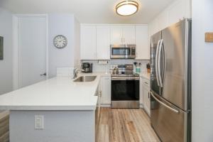 a kitchen with white cabinets and a stainless steel refrigerator at F204 - Cozy Seaview Condo in Oceanside