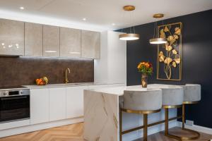 una cocina con armarios blancos y una barra con taburetes en London's Modern Nuance Apartment - Battersea, en Londres