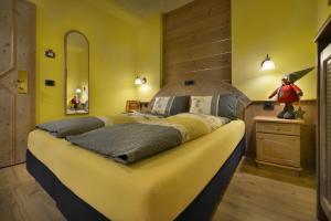 a bedroom with a large bed with yellow walls at Hotel Piccolo Mondo in Livigno
