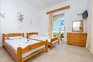 two beds in a room with a view of the ocean at Tassos & Marios Apartments I in Laganas