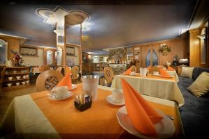 une salle à manger avec deux tables et des serviettes orange dans l'établissement Hotel Piccolo Mondo, à Livigno