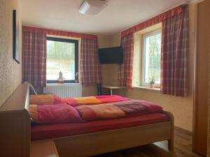 Bett in einem Zimmer mit zwei Fenstern in der Unterkunft Pension Pöhlbergblick Annaberg in Annaberg-Buchholz
