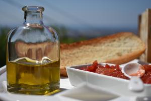 a bottle of oil next to a plate of food and bread at Casa KiSi Cottage, Rural Boutique Bed & Breakfast in Málaga
