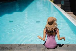 a woman in a hat sitting next to a swimming pool at The Diplomat Hotel in Sliema