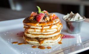 a stack of pancakes with strawberries and syrup on a plate at The Diplomat Hotel in Sliema