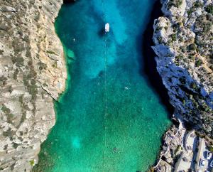an aerial view of a beach with a boat in the water at The Diplomat Hotel in Sliema