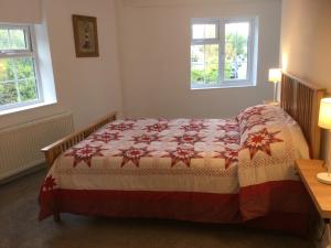 a bedroom with a bed and two windows at Crossways Corner Cottage in Gunnislake