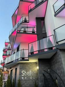 a building with glass balconies and pink lights on it at Stella in Ternopilʼ