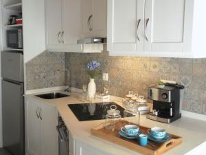 a kitchen with white cabinets and a wooden tray with cups at Alo Baía São Lourenço in Santa Bárbara