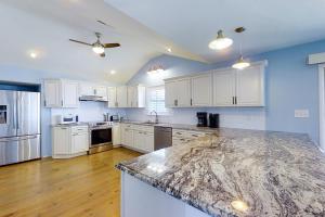 a kitchen with white cabinets and a marble counter top at Dock of the Bay in Atlantic Beach