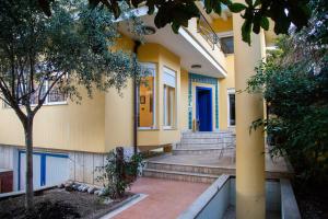 a yellow building with stairs and a blue door at Blue Door Hostel in Tirana