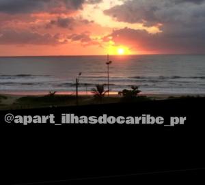 a sunset on the beach with the ocean and the sun at Apto Cond Ilhas do Caribe - Pr - Beira Mar in Matinhos