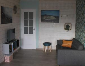 a living room with a couch and a television at Gîte de la Tuillère, maison contemporaine en bois avec vue et piscine in Saint-Aulaire