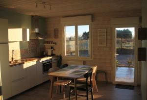une cuisine avec une table et des chaises dans l'établissement Gîte de la Tuillère, maison contemporaine en bois avec vue et piscine, à Saint-Aulaire