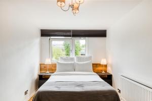 a bedroom with a bed with two lamps and a window at Homely 4 Bedroom House in Brixton in London