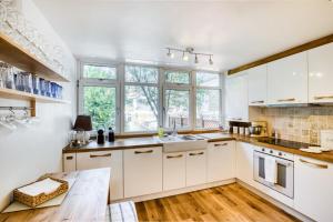 a kitchen with white cabinets and a large window at Homely 4 Bedroom House in Brixton in London