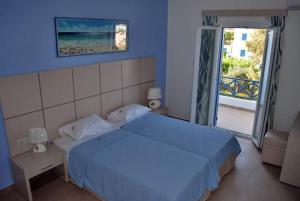 a blue bedroom with a bed and a large window at Thealos in Azolimnos