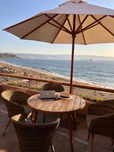 a table with a laptop and an umbrella on the beach at Condesa del Mar in Viña del Mar