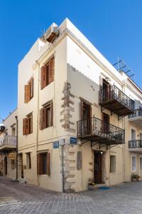 a white building with wooden windows and balconies at Hera Studios in Chania