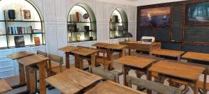 une salle de classe avec des tables, des chaises et des étagères en bois dans l'établissement Luz Charming Houses, à Fátima