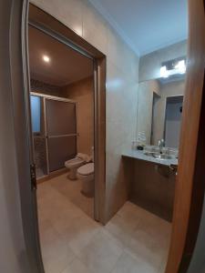 uma casa de banho com um WC, um lavatório e um espelho. em Via Almafuerte em Concepción del Uruguay