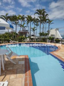 a large swimming pool with a table and palm trees at Apto Cond Ilhas do Caribe - Pr - Beira Mar in Matinhos