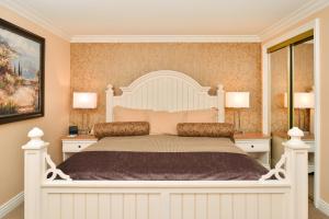 a bedroom with a large white bed with two lamps at Dana Point Marina Inn in Dana Point
