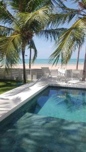 una piscina junto a una playa con palmeras en Nordestina Casa de Mar, en Icaraí