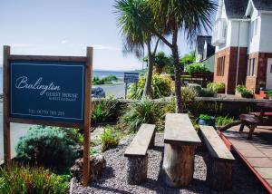 ein Schild für eine Pension mit zwei Bänken in der Unterkunft Burlington Guest House in Whiting Bay