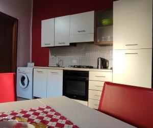 パレルモにあるCasa Samuのキッチン(白いキャビネット、テーブル、赤い椅子付)