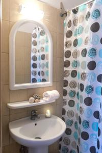 a bathroom with a sink and a mirror and a shower curtain at Sueño Luxury Apartments in Polykhrono