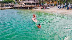 dos personas en una tabla de paddle en el agua en Palmarito Beach Hotel, en Tierra Bomba