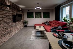 a living room with a red couch and a brick wall at Apartament Chopin in Sanok