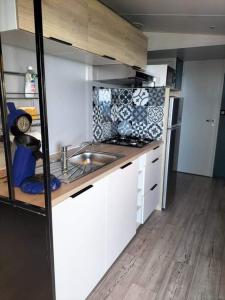 una pequeña cocina con armarios blancos y fregadero en Charmant Mobil home avec Vue mer exceptionnelle, en Saint-Raphaël